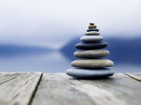 Zen balancing pebbles next to a misty lake.